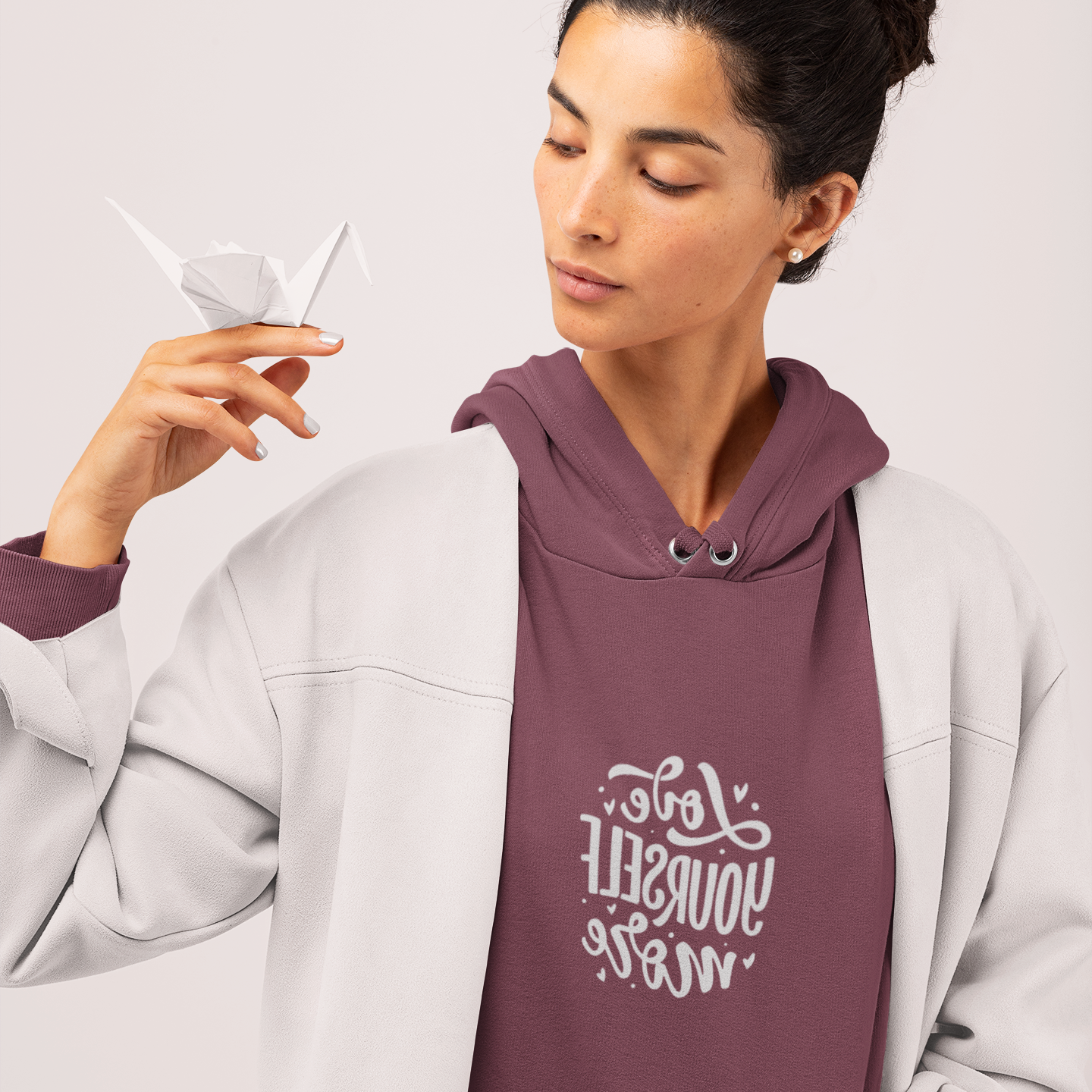 Woman wearing a maroon hoodie with text design on a light gray background